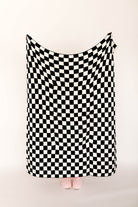 Black and white checkered blanket draped over a person on a beige background