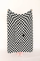 Black and white checkered blanket draped over a person on a white background