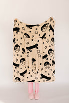 Beige blanket with black smiley and skateboard pattern on a plain background