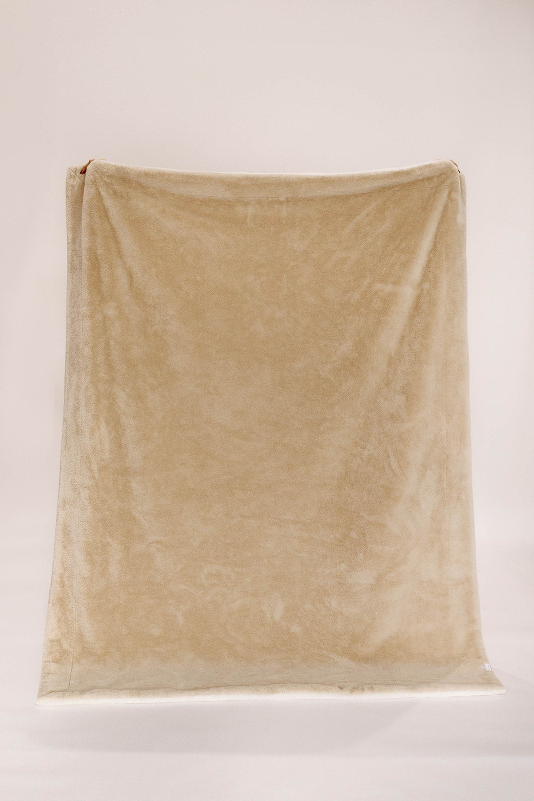 Beige blanket draped over a white surface