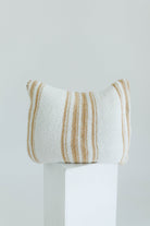 Striped pillow on a white pedestal against a light gray background