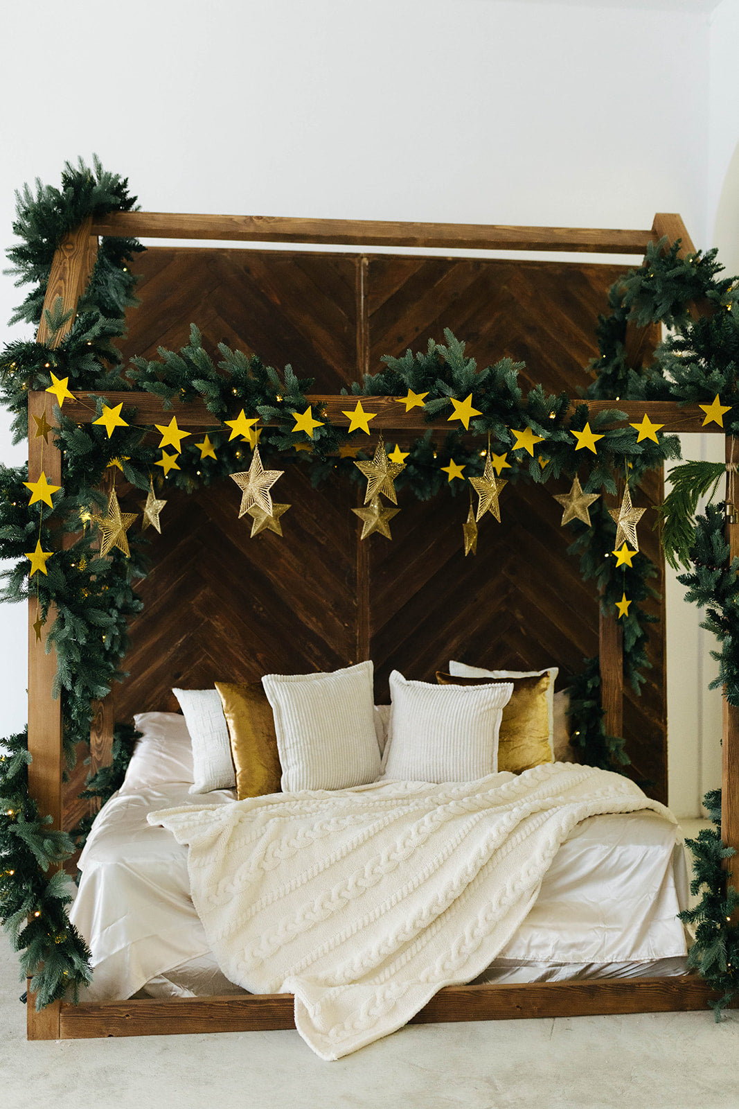 Decorative Christmas bed with garlands, stars, and pillows on a wooden headboard.