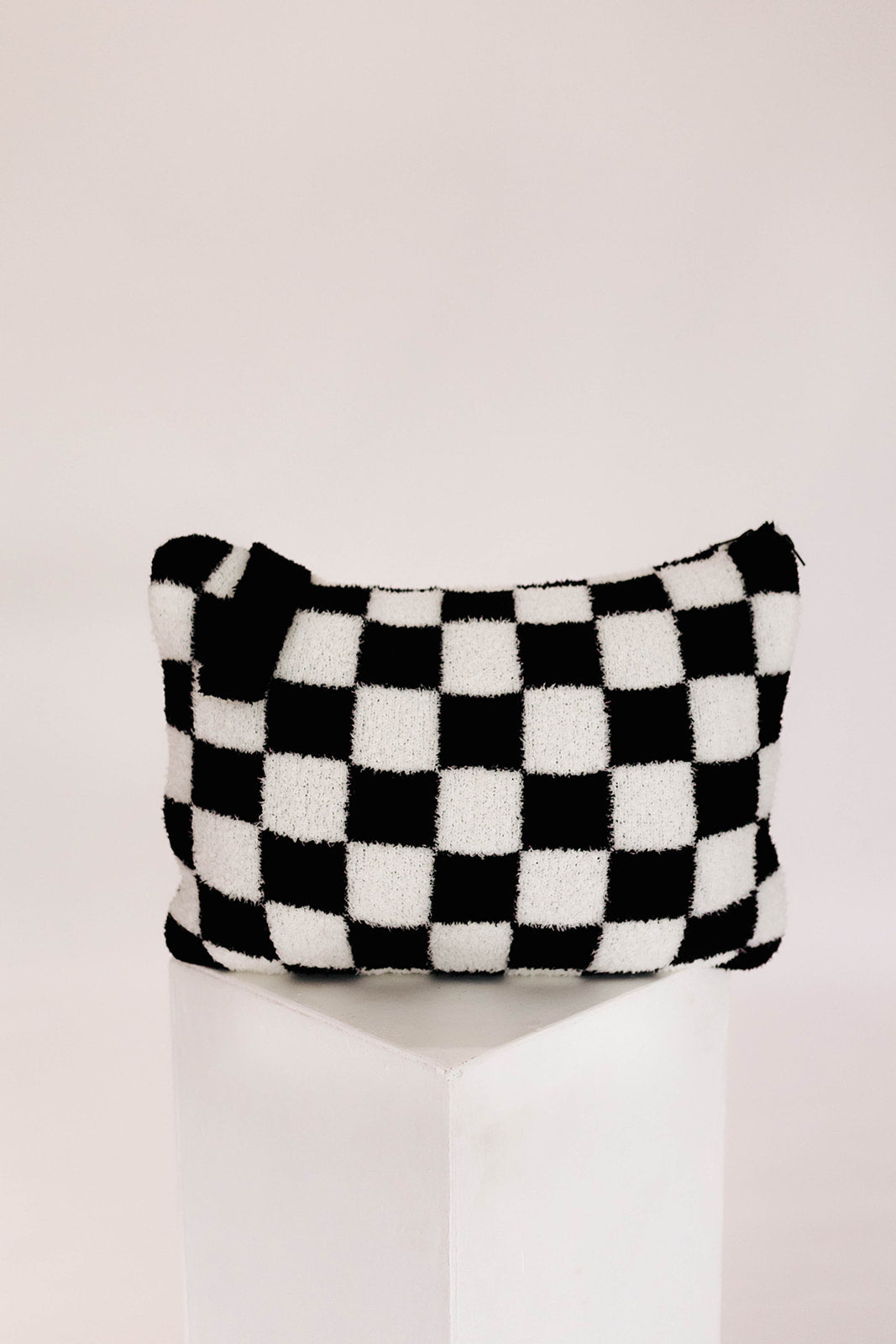 Black and white checkered pillow on a white background