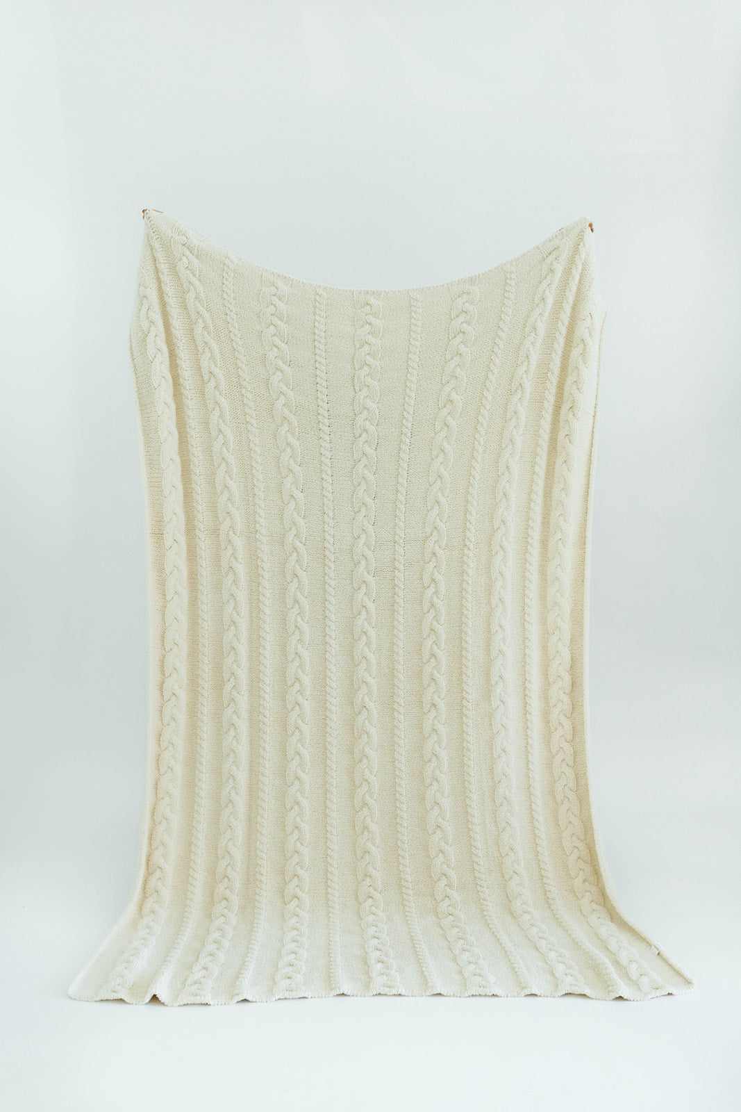 Cream-colored knitted blanket on a white background