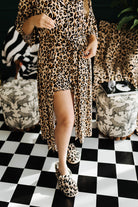 Person wearing a leopard print outfit on a black and white checkered floor.