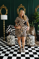 Woman in leopard print outfit holding a quillow in a room with decorative mirrors and furniture.