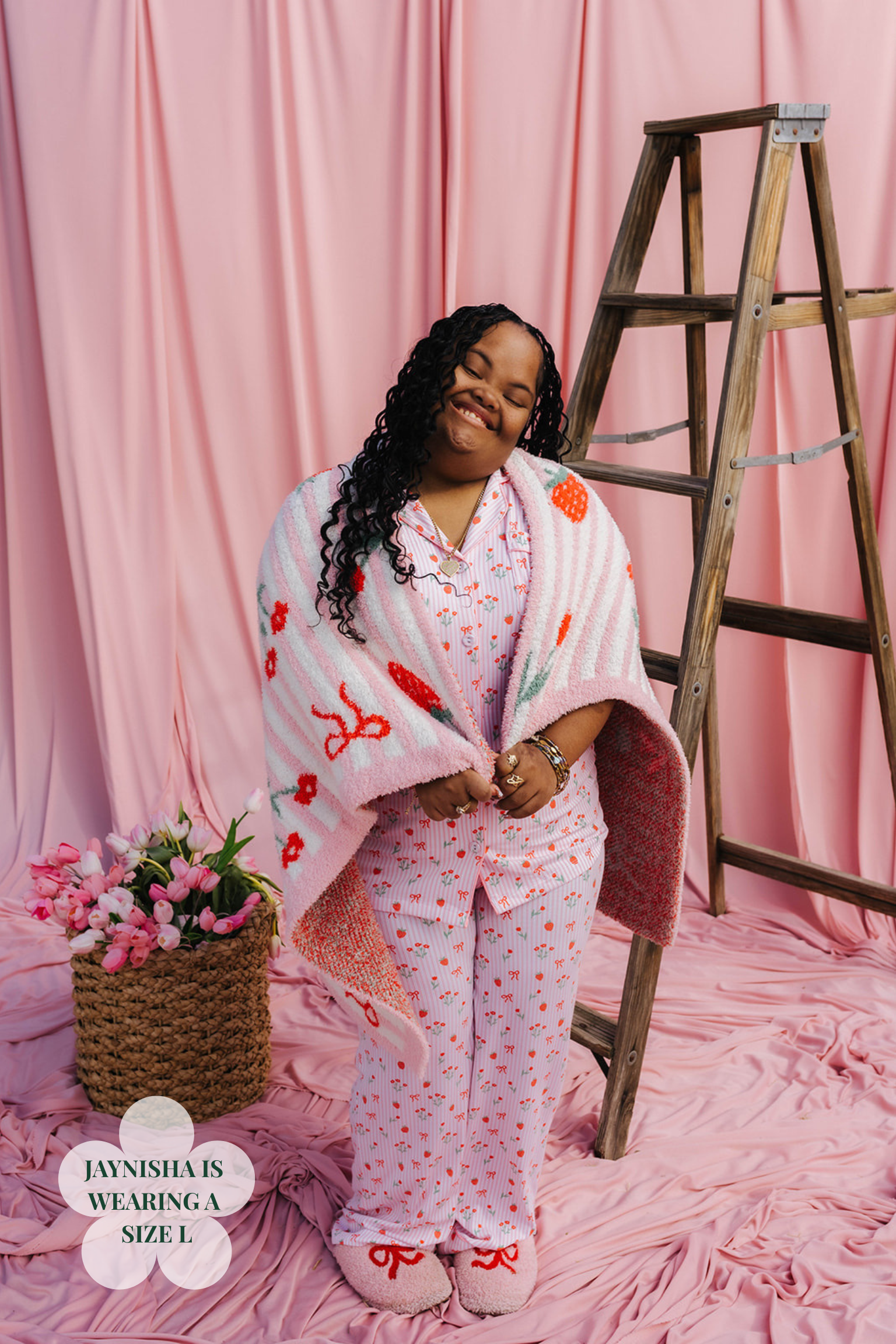 Woman in pink floral pajama set with matching robe against a pink curtain background