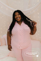 Woman wearing pink polka dot pajamas against a softly lit background
