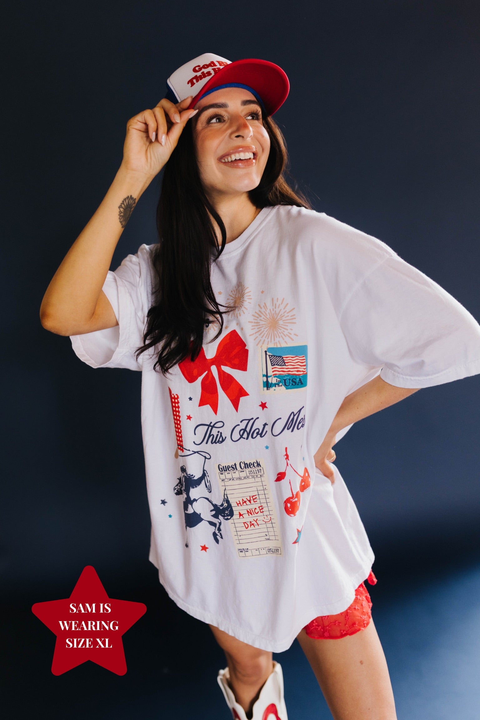 Woman wearing a white graphic t-shirt and red cap against a dark background