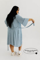 model with back turned showing blue striped robe and how the tie is attached to the robe 