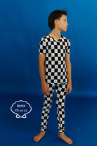 Child wearing a black and white checkered pj set on a blue background size 10/12