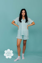 Woman wearing teal check pajama set against a teal background
