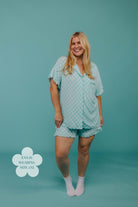 Woman wearing a teal patterned pj set on a teal background