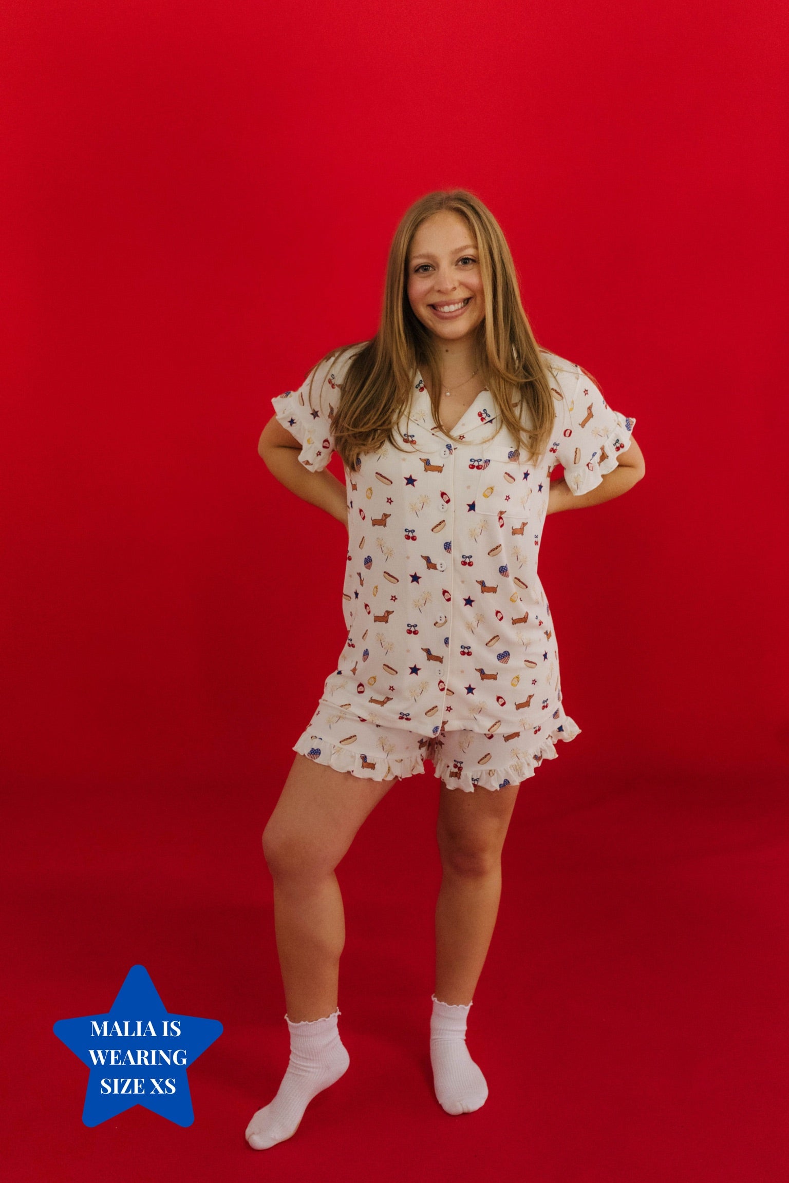 Woman wearing a white pajama set with small 4th of july prints on a red background