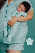 Person wearing a matching teal checkered outfit with a baby
