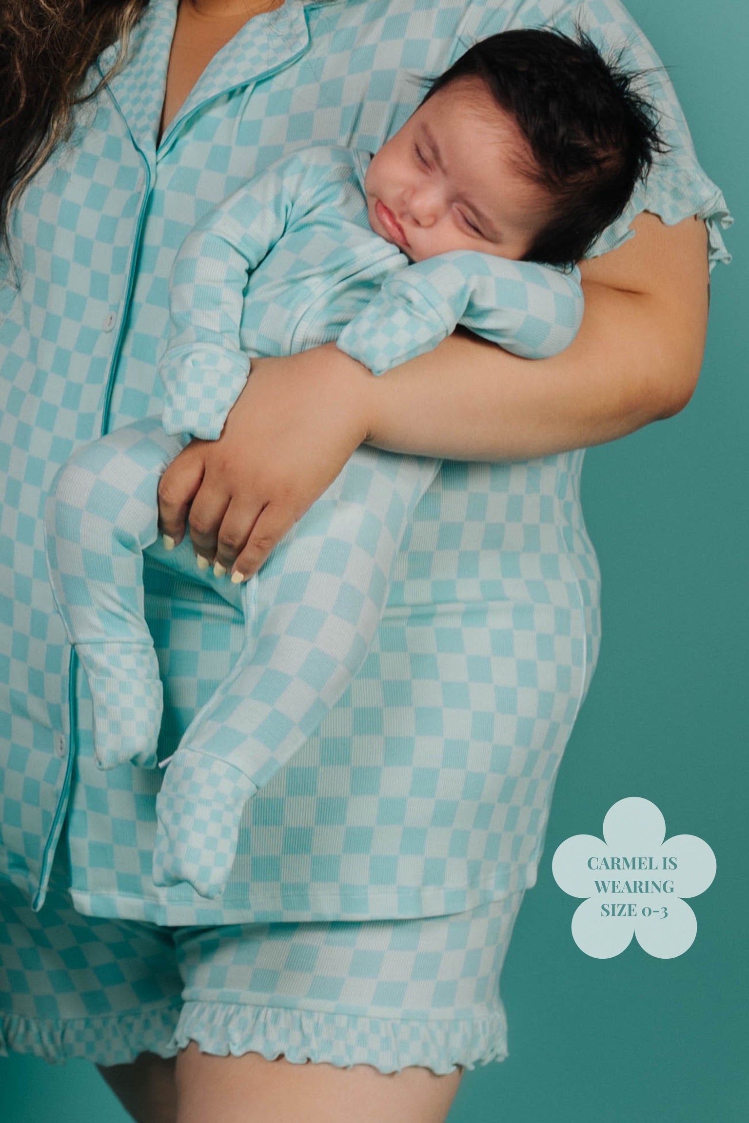 Person wearing a matching teal checkered outfit with a baby