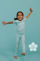 Child wearing a check pajama set on a teal background