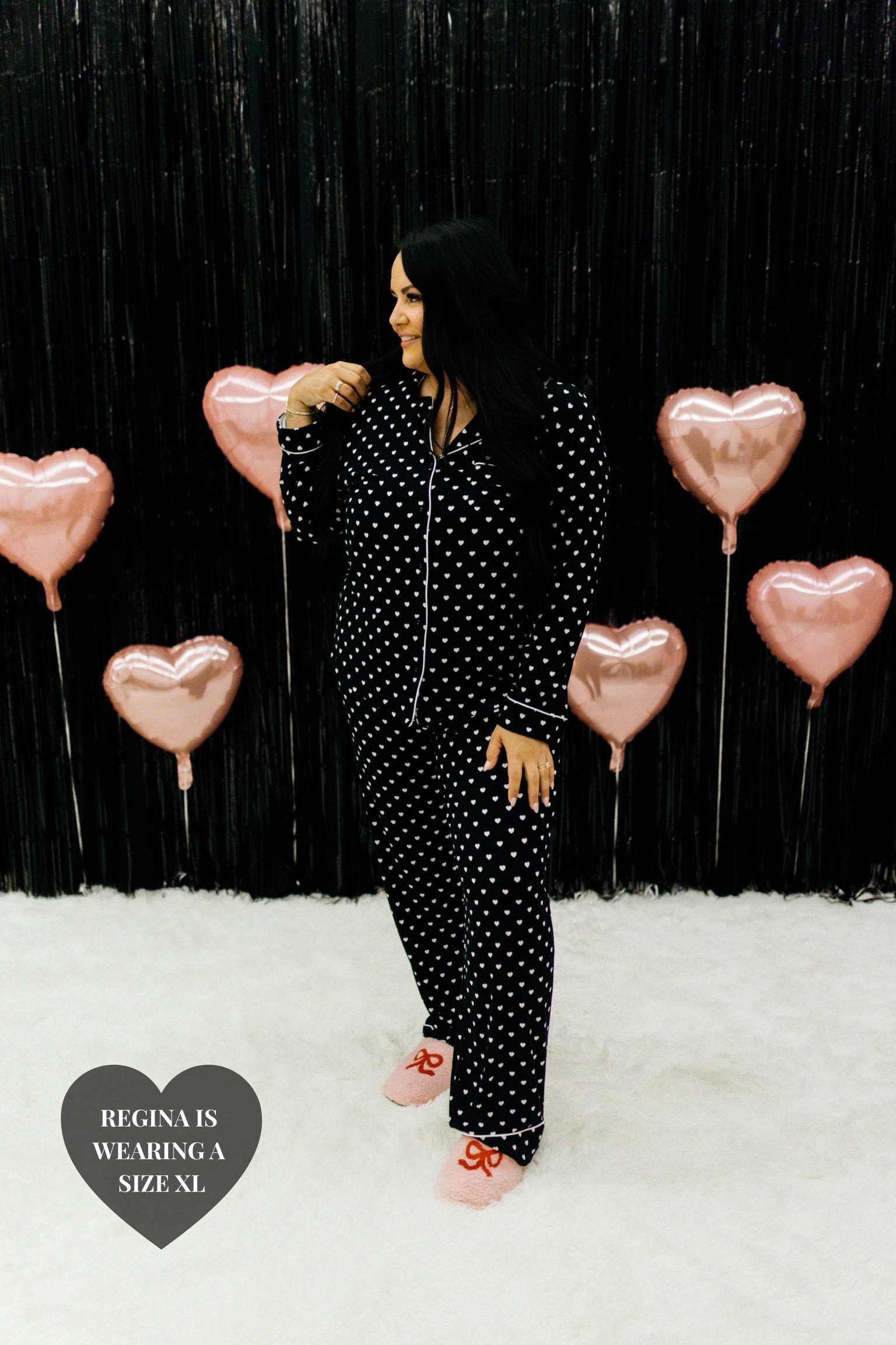 Regina holding her hair with one hand in showing the 2xl black heart pjs
