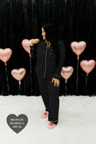 Regina holding her hair with one hand in showing the 2xl black heart pjs