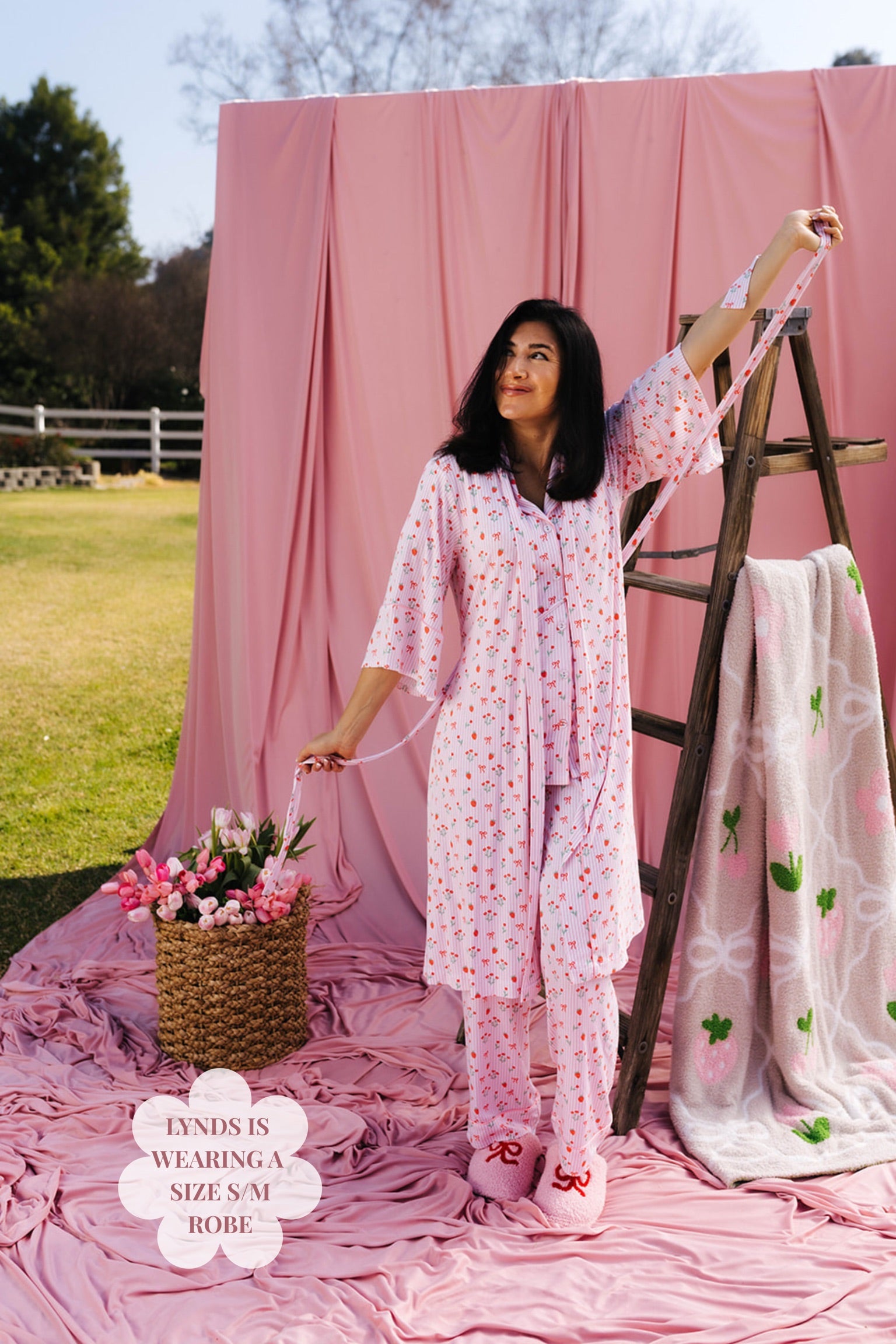Woman in a pink floral outfit standing next to a ladder