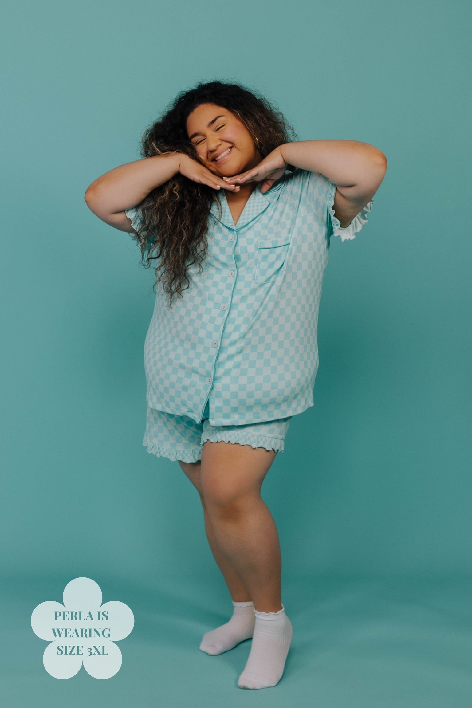 Woman wearing a teal pajama set against a teal background