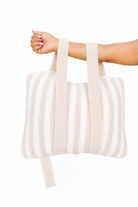 Person holding striped quillow by their arm 