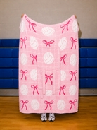 pink quillow full blanket size with a white net in the background and volleyballs and bows
