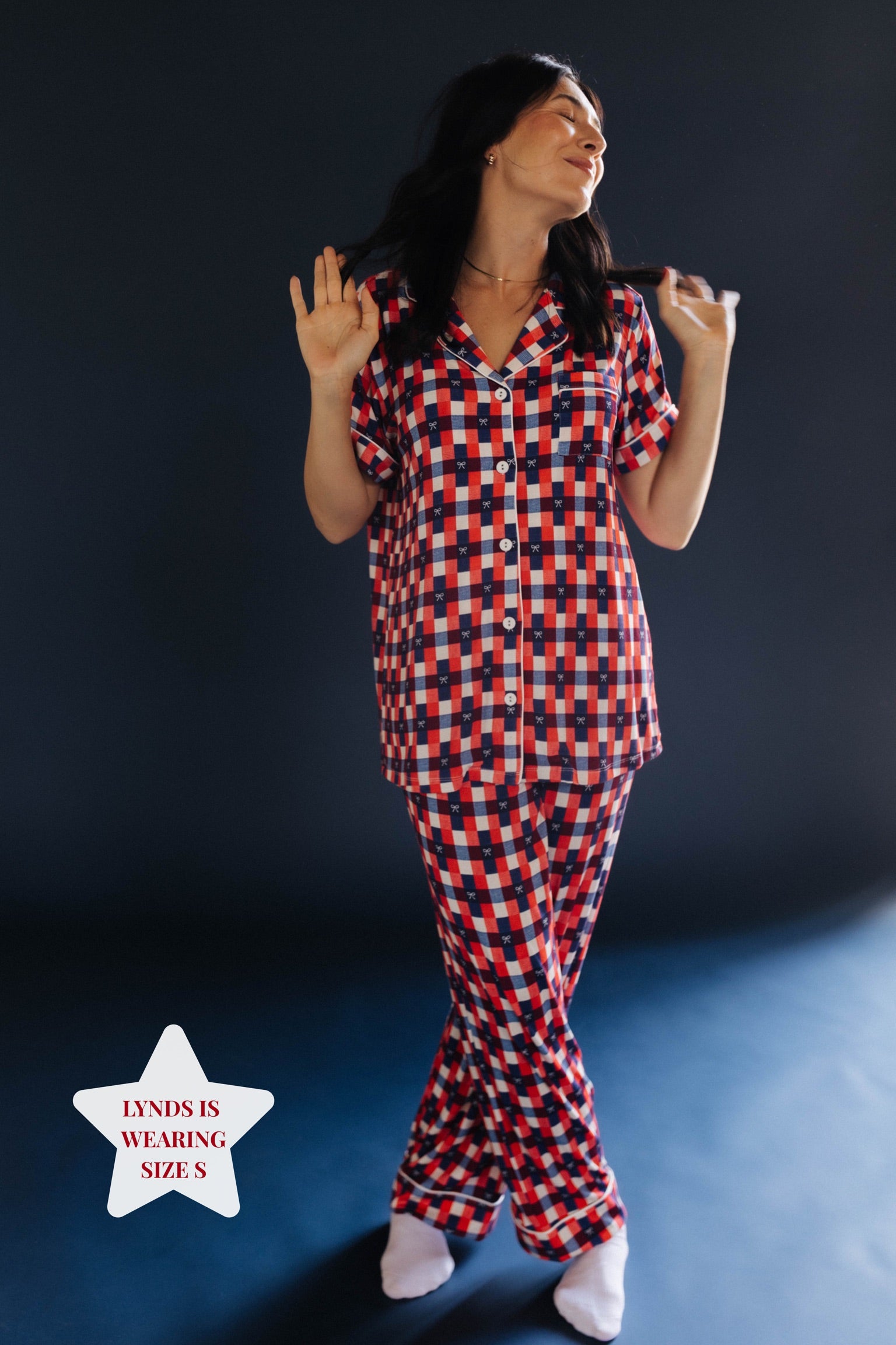 Person wearing a red and blue gingham pj set on blue background 