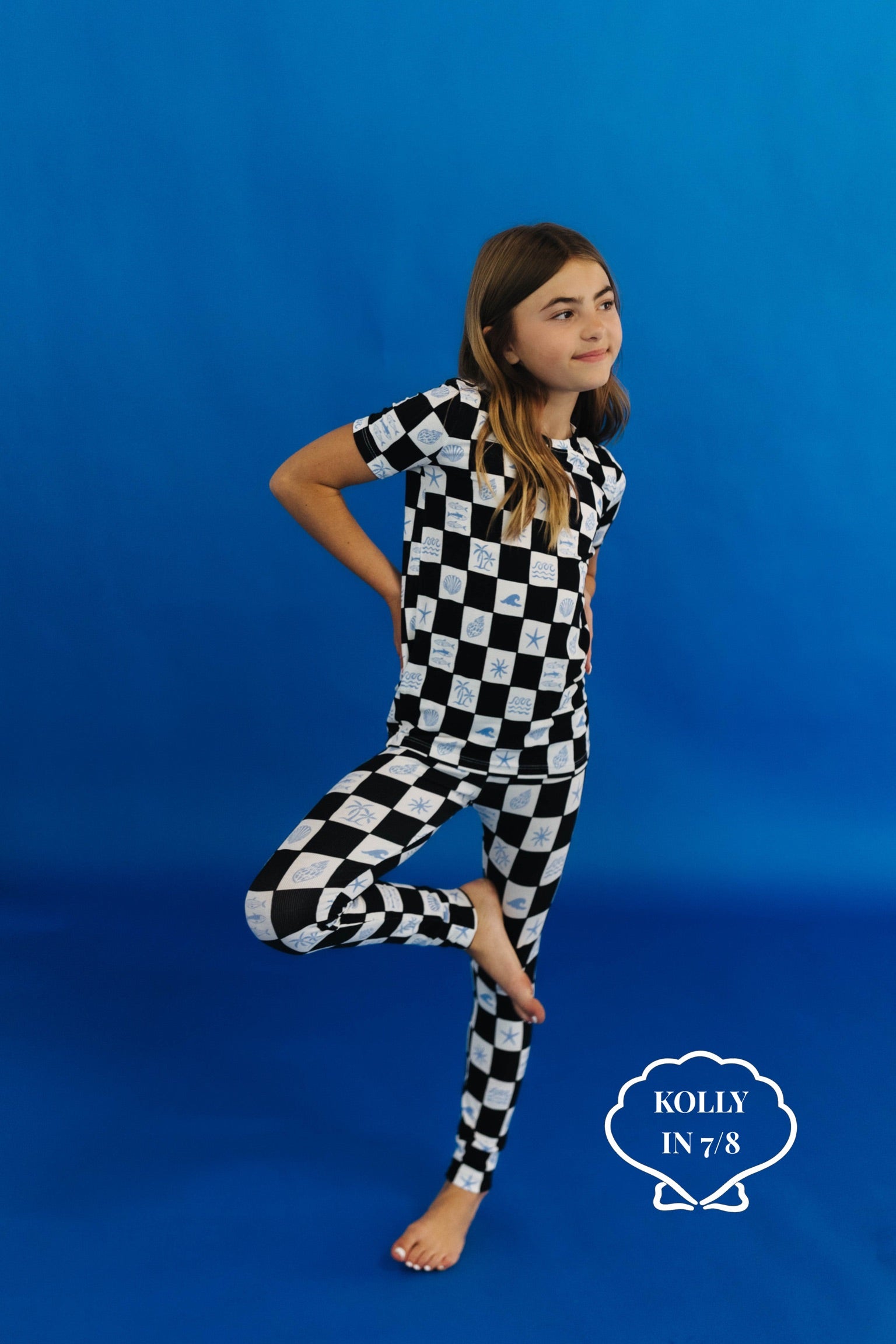 Child wearing a black and white checkered pj set on a blue background size 7/8