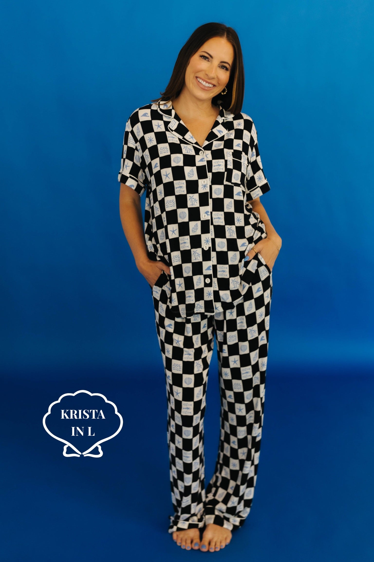 Woman wearing a black and white checkered pajama set against a blue background Krista is size L