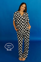 Woman wearing a black and white checkered pajama set against a blue background Krista is size L