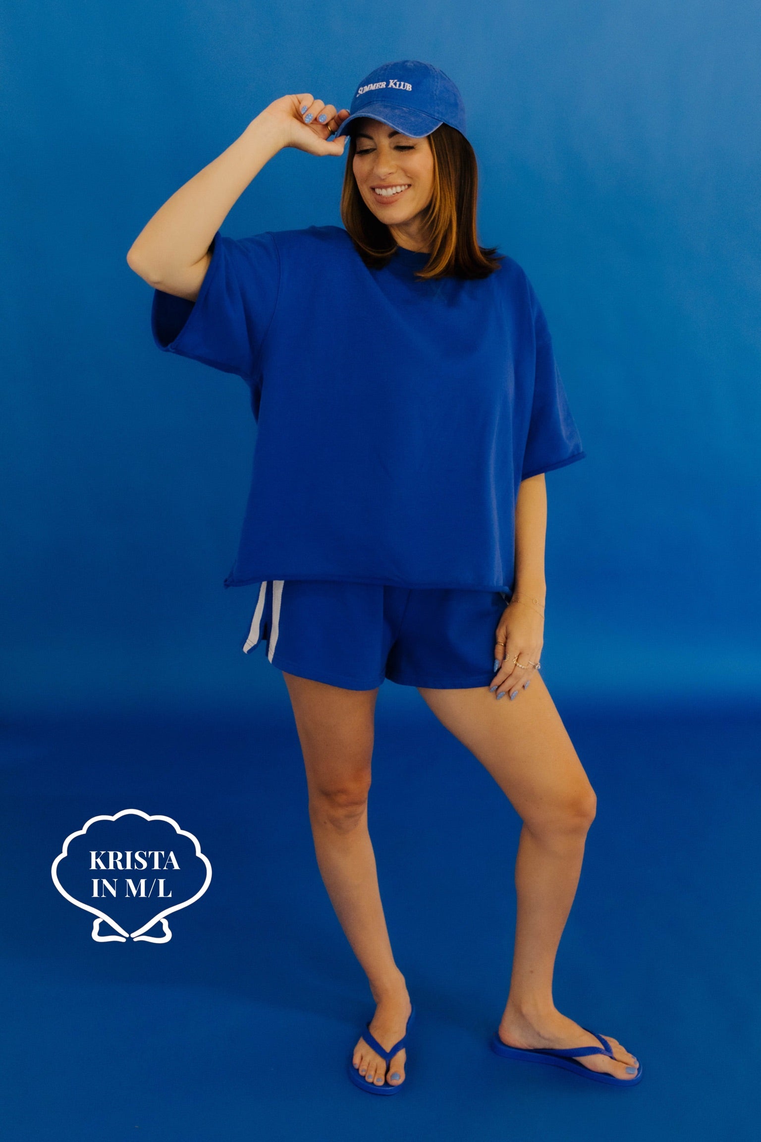 Woman wearing a blue outfit with a matching cap against a blue background