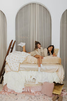 models krista and kolly smiling on multi-layered bed wearing lace polka dot pajamas and showing off the polka dot quillow 