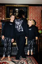 Adult and children standing together in matching Spooky Season sweatshirts