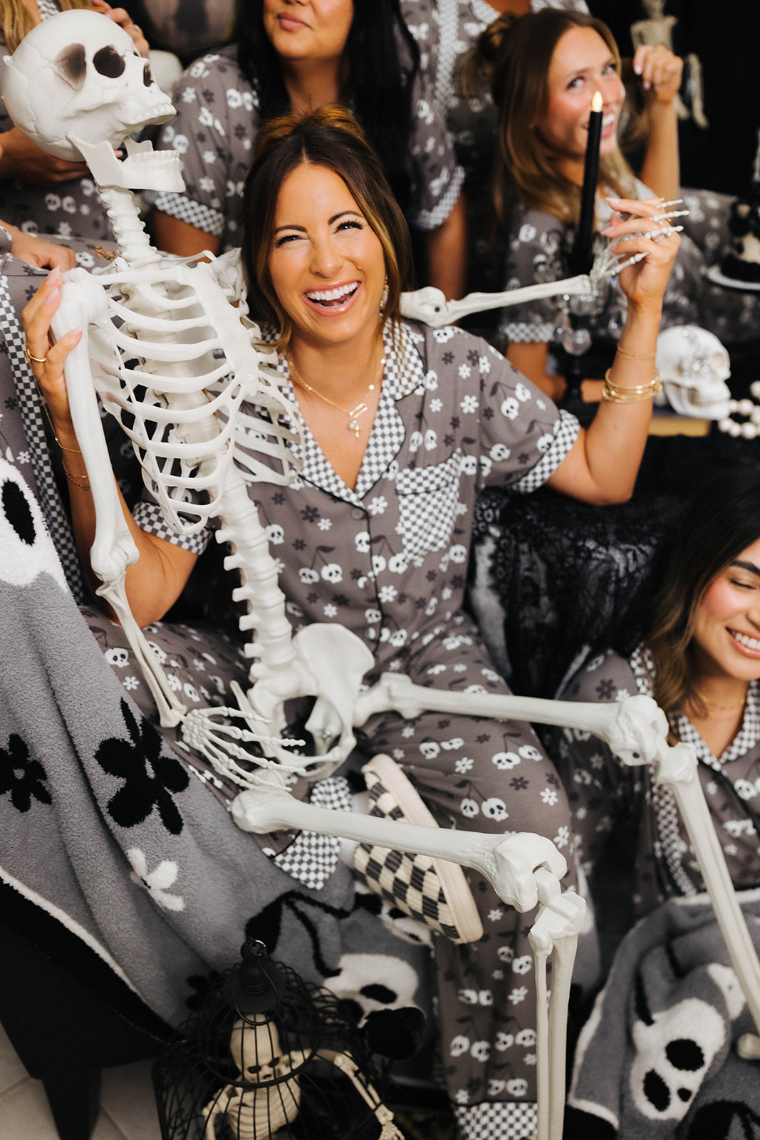 Woman smiling wearing skeleton pajamas with a skeleton wrapped around her 