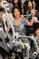 Woman smiling wearing skeleton pajamas with a skeleton wrapped around her 