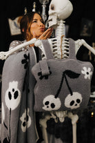 model krista doing kissy face to skeleton wearing the skelly backpack/wristlet quillow