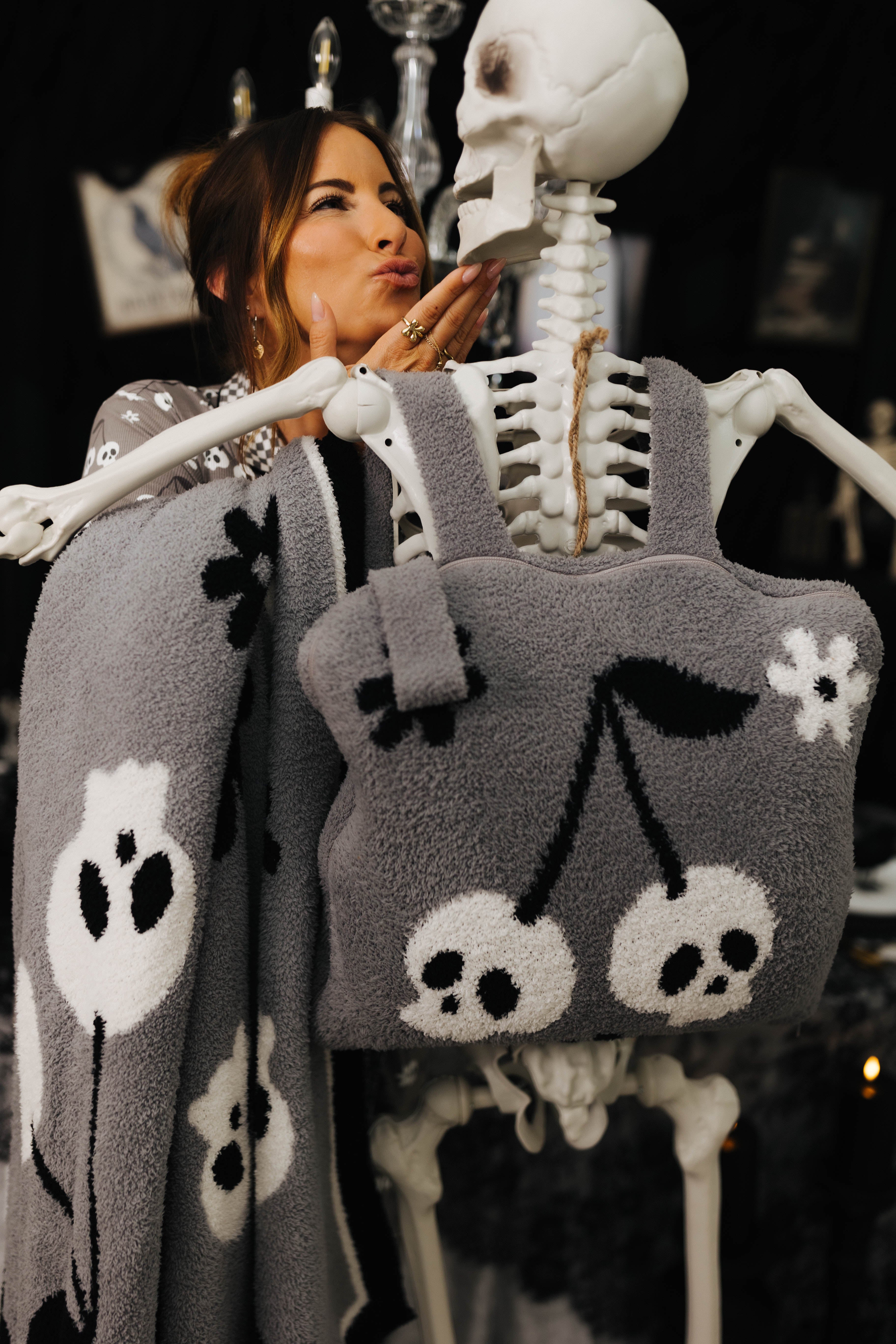 model krista doing kissy face to skeleton wearing the skelly backpack/wristlet quillow