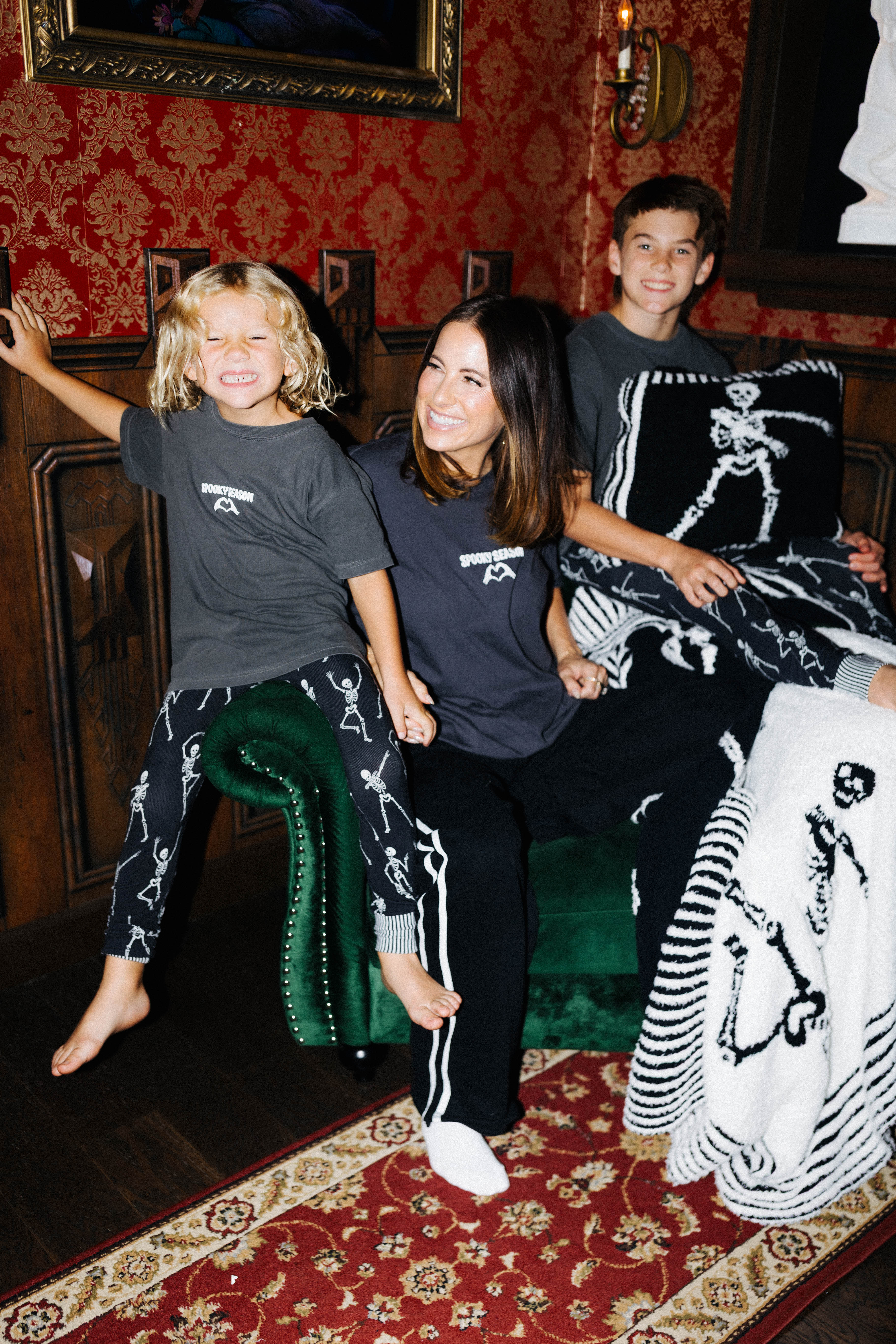 Family wearing Spooky Season tees with Skelly quillows and blanket