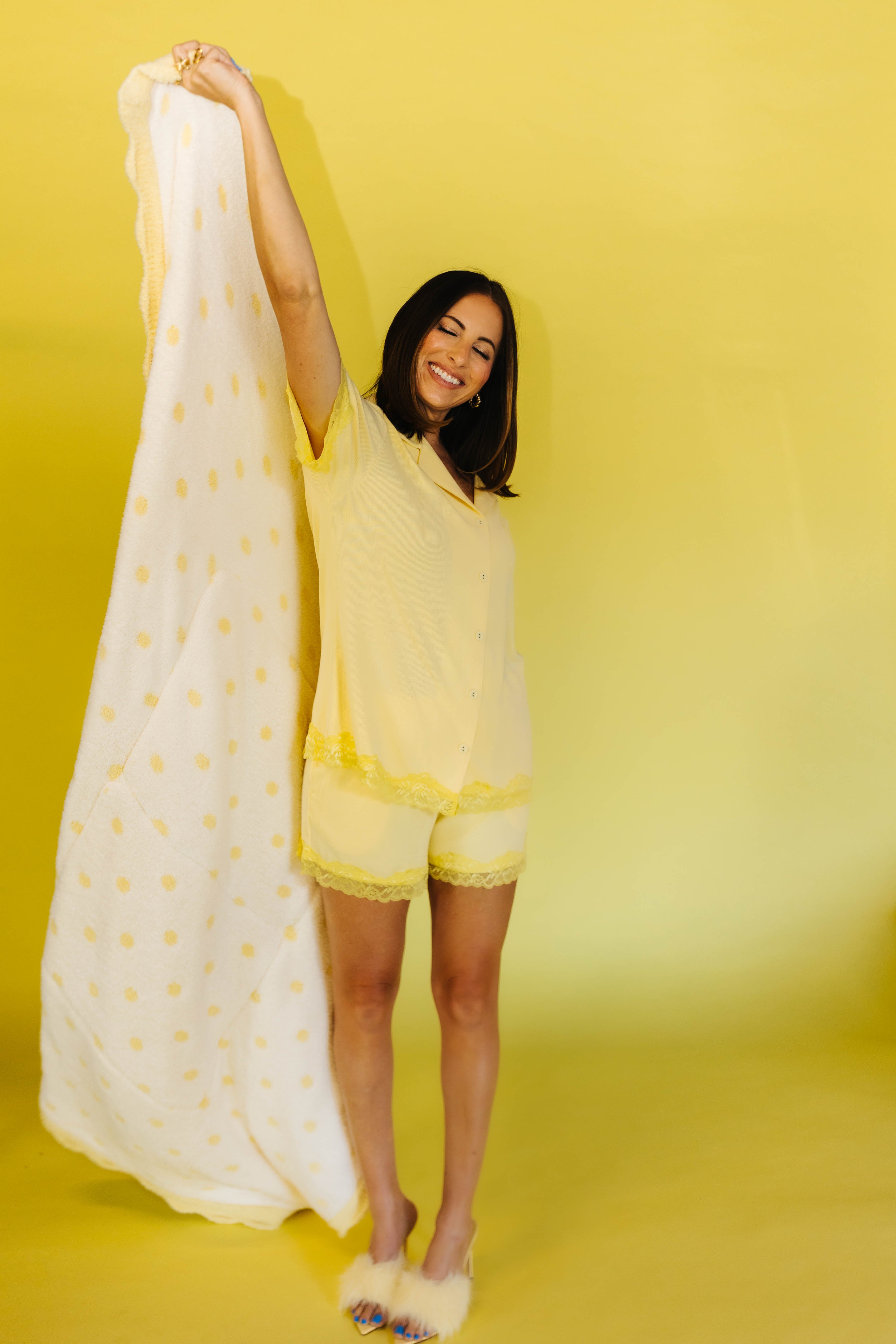 krista holding up the quiillow in the yellow pjs on yellow background