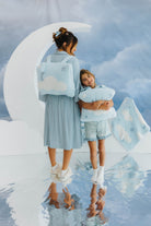 models krista and kolly wearing cloud backpack/wristlet quillow on back and holding it with cloud and moon decorations in the back 