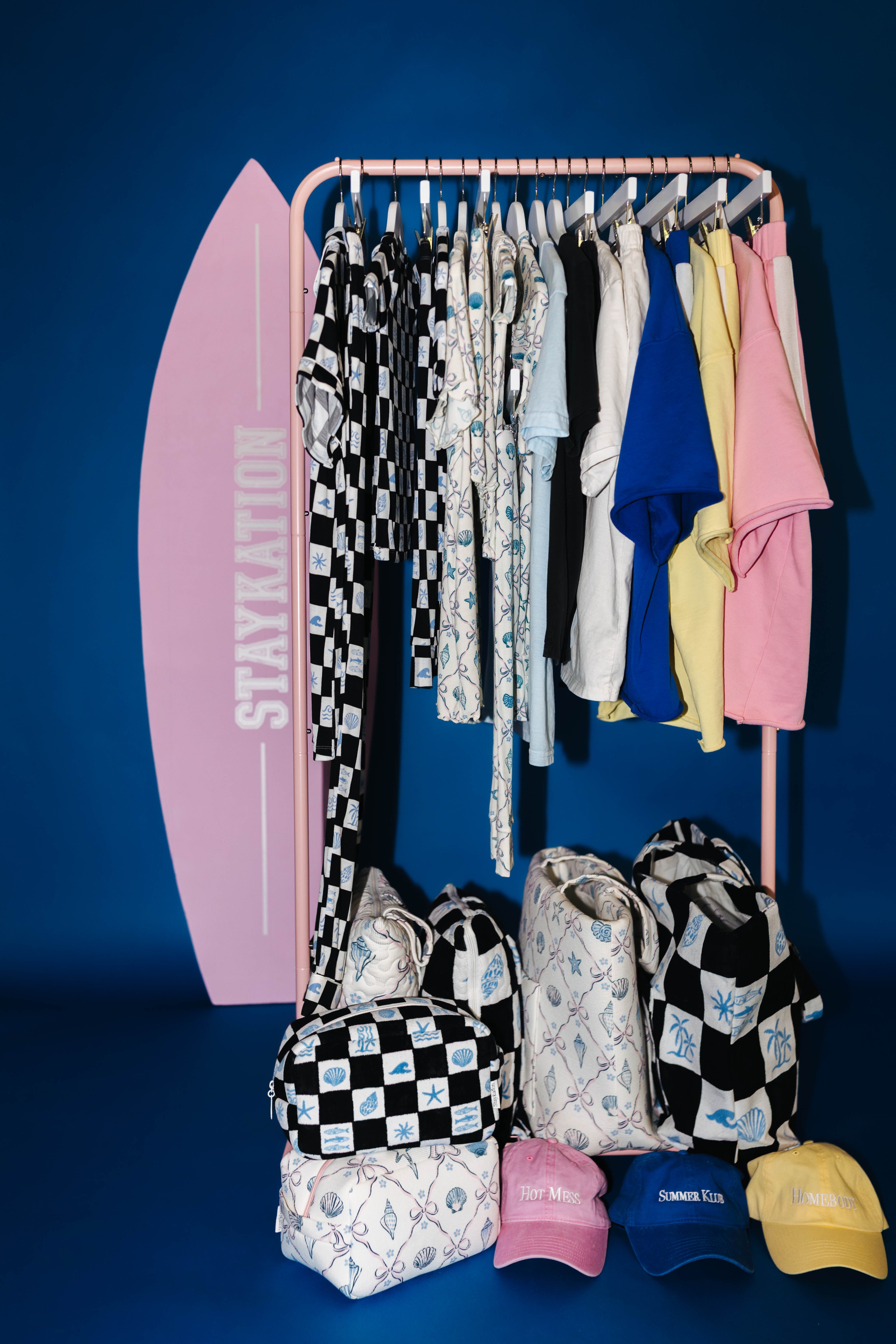 Clothing rack with clothes, bags, and hats against a blue background