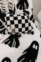 black check quillow sitting in the lap of skeleton with ghost blanket underneath 