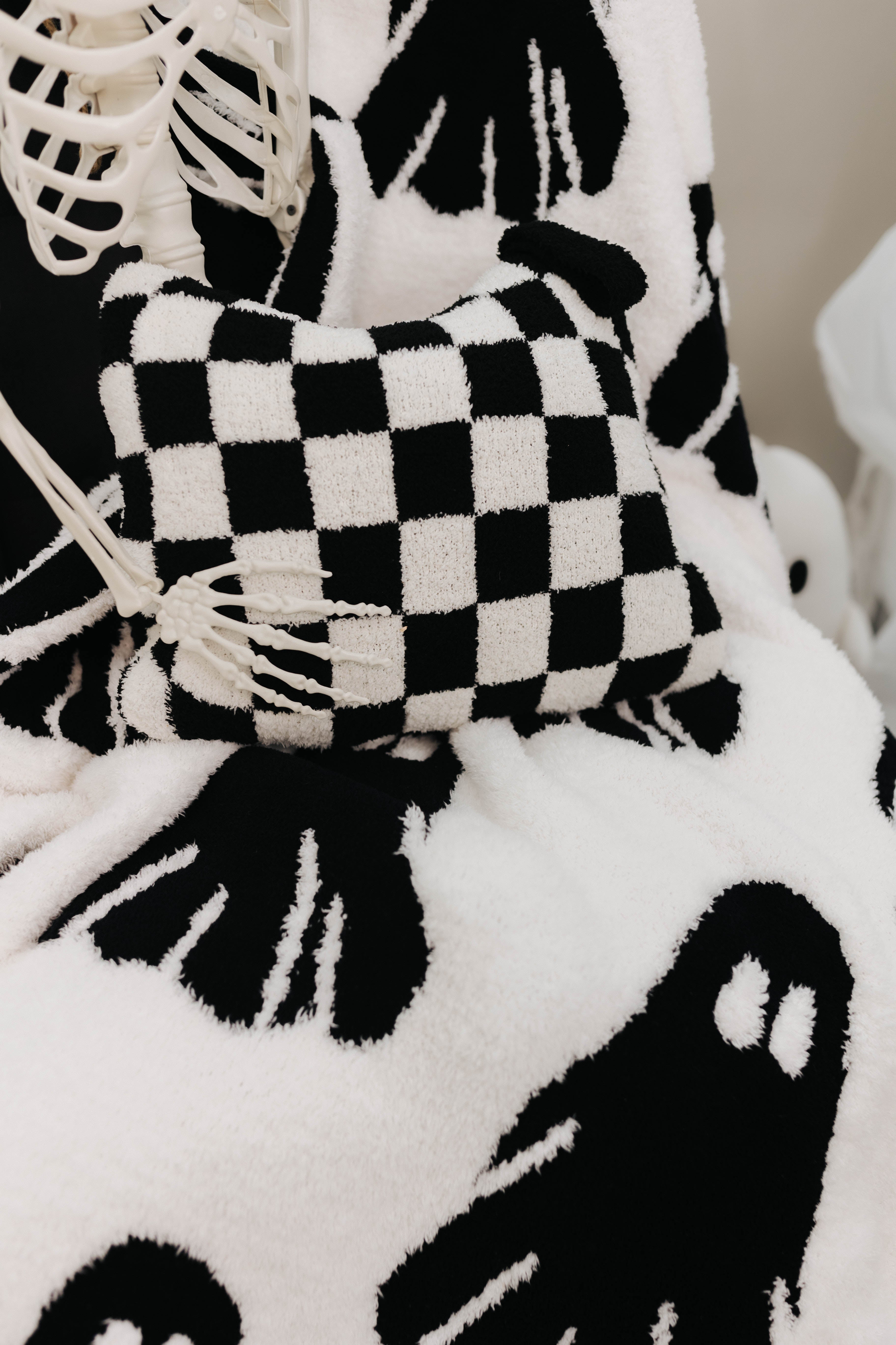 black check quillow sitting in the lap of skeleton with ghost blanket underneath 
