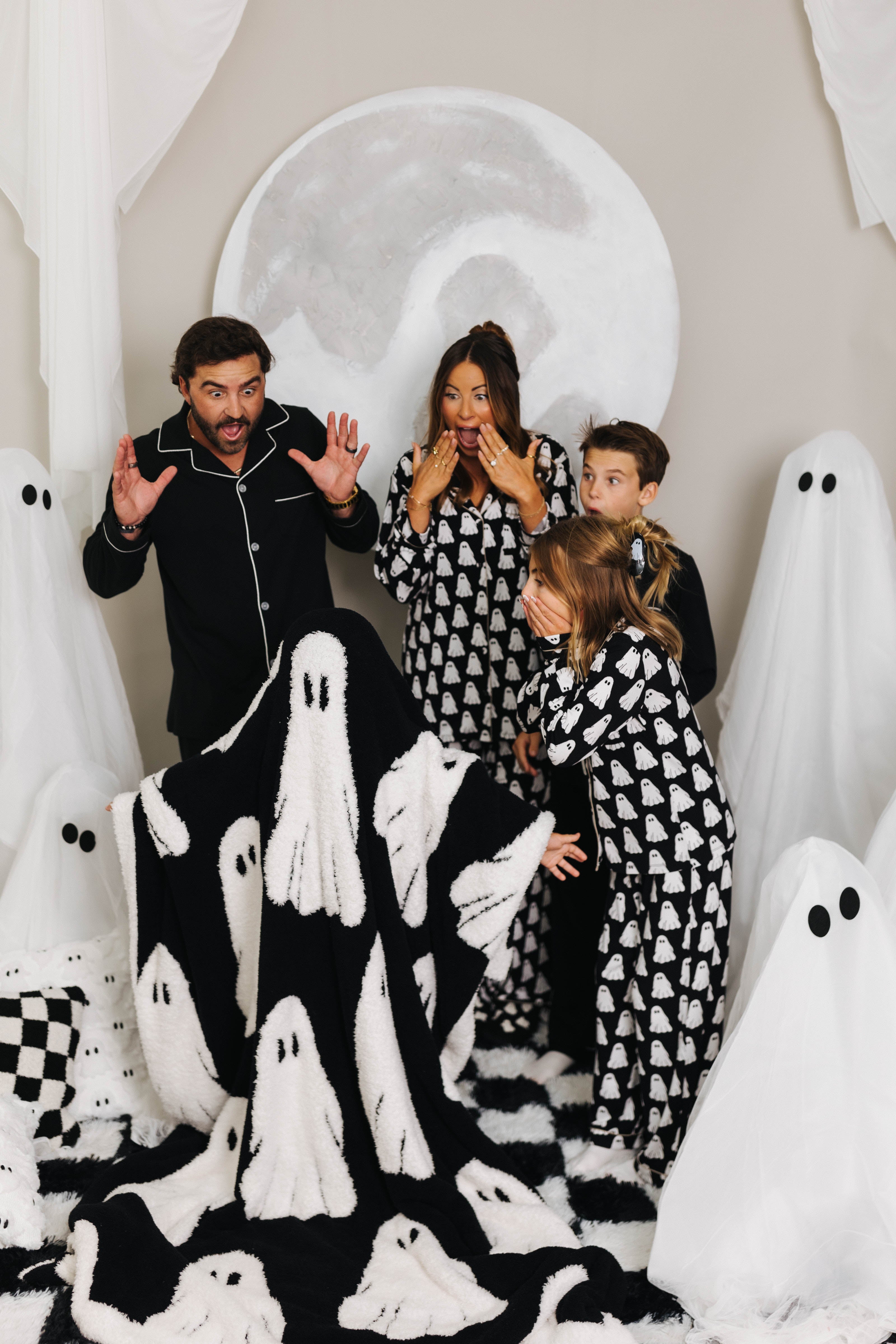 models making scared face looking at model wearing the ghost blanket over head and body 