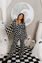 model krista with ghost decorations in the background wearing ghost pajamas holding black check quillow over shoulder