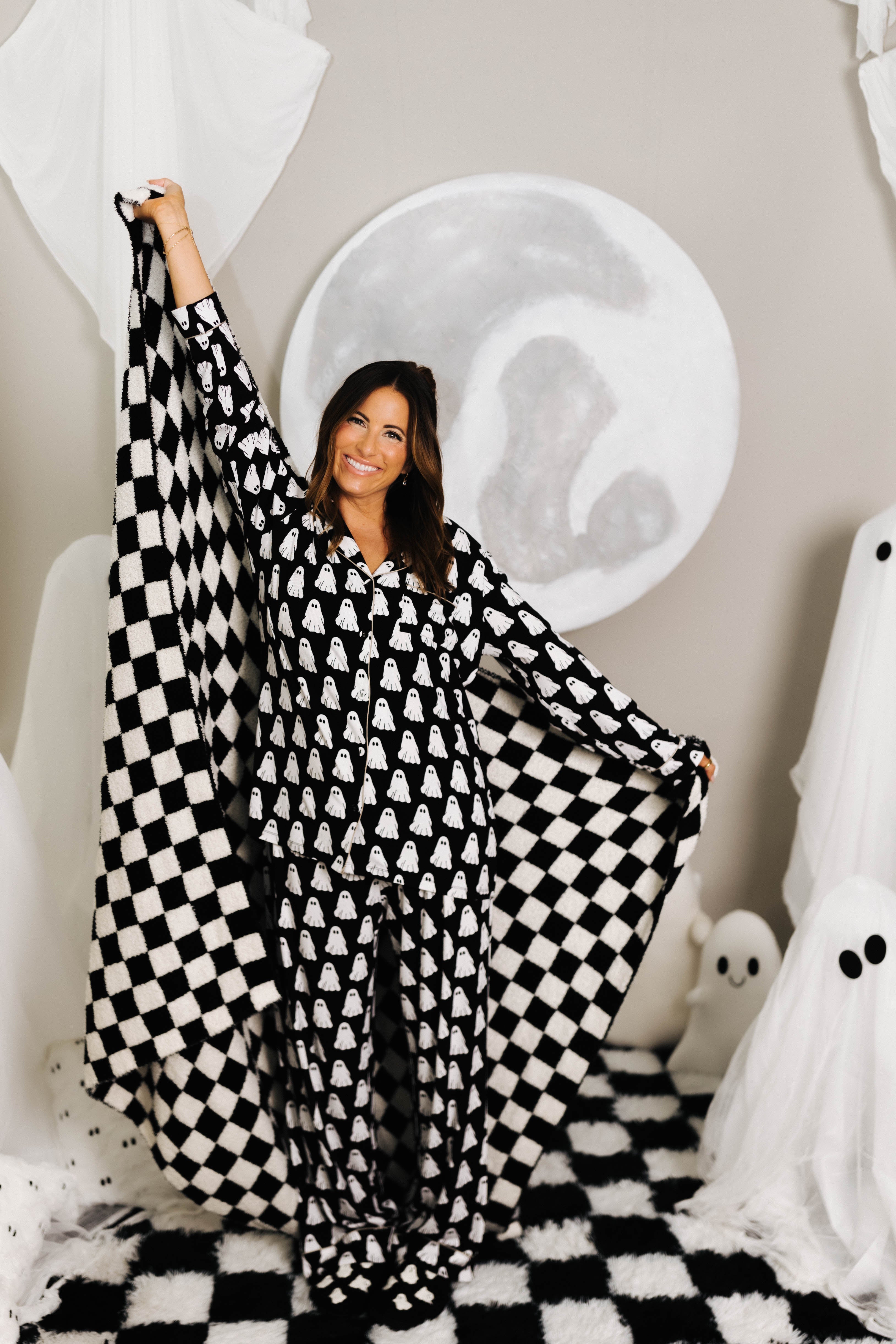model krista smiling holding the black check quillow opened with ghost decorations in the background 