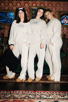 Three models wearing tan Hot Mess sweatshirts and matching pants