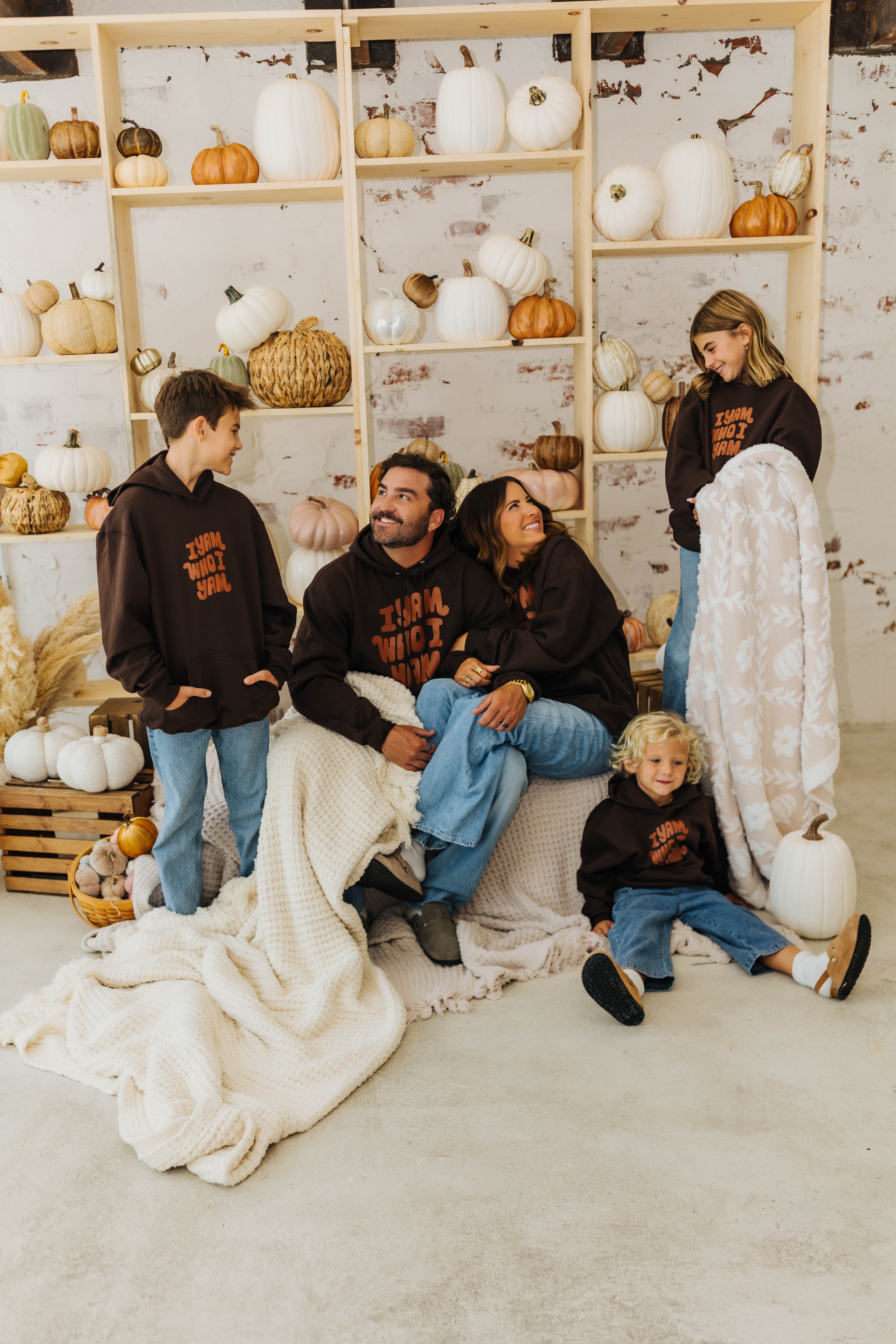 family smiling at each other with waffle blankets wrapped around them and holding pumpkin blanket 