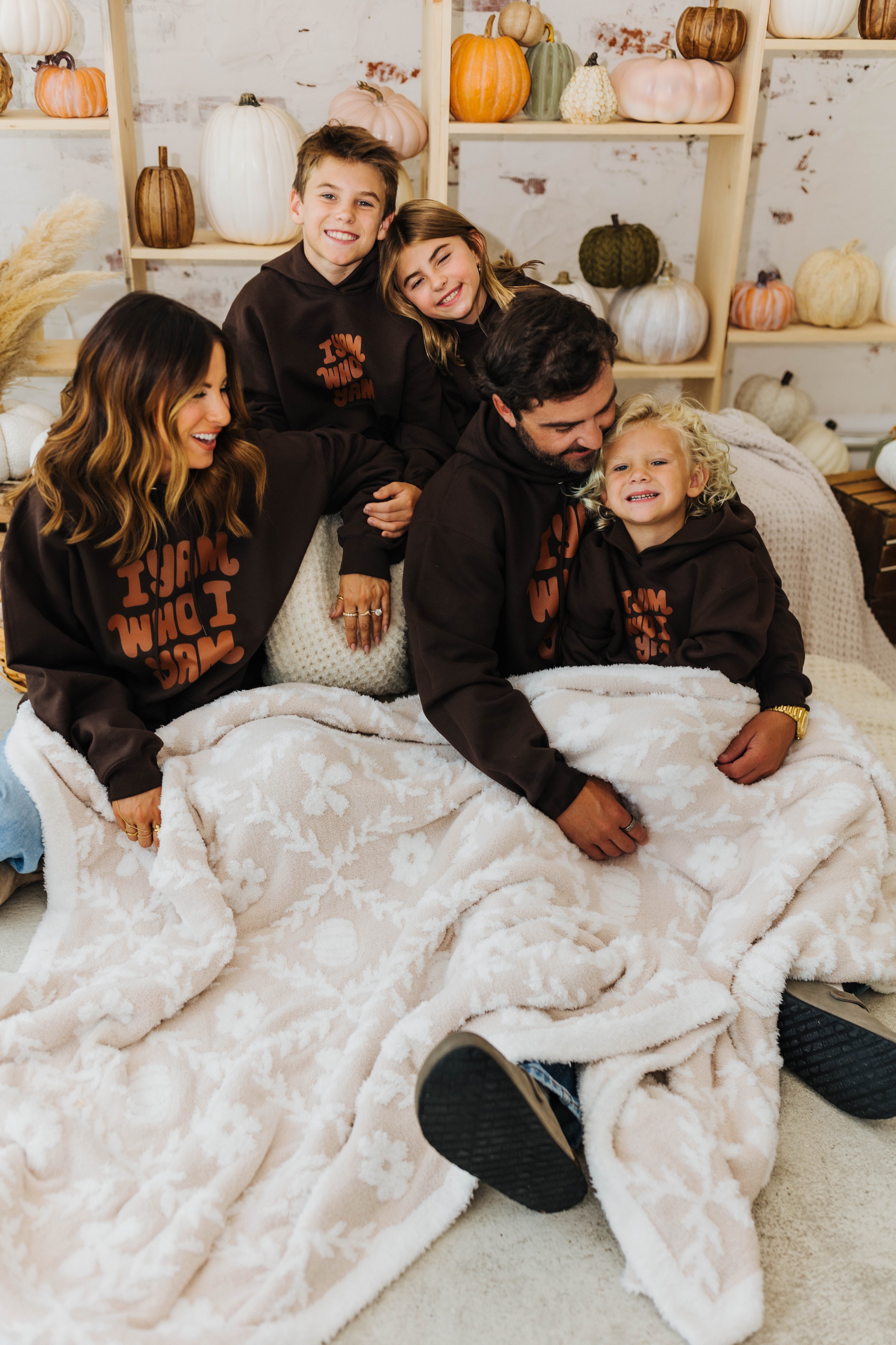 family looking at each other smiling with pumpkin blanket on their lap 